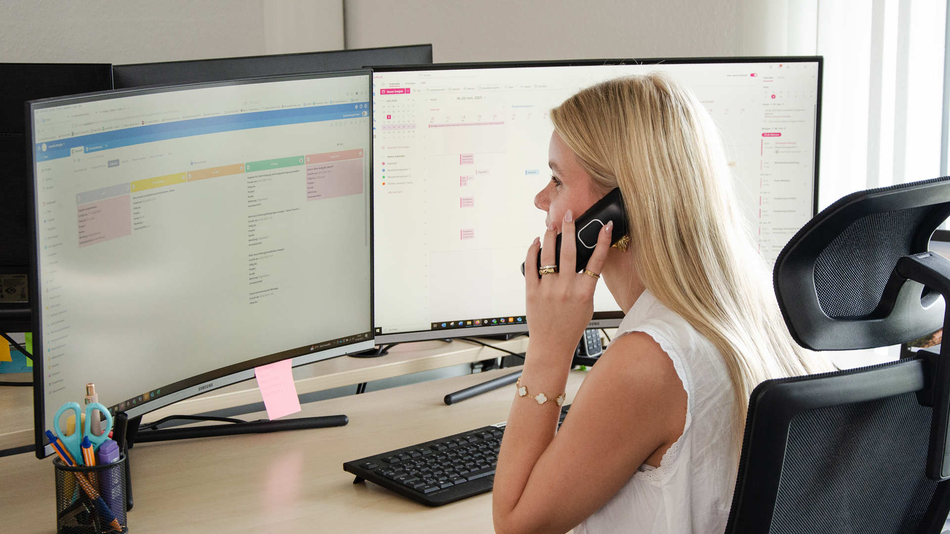 Abbildung einer Büromitarbeiterin der LEONDA GmbH, sitzend vor dem PC mit einem Telefon am Ohr.
