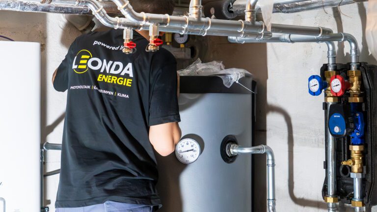 Abbildung eines Mitarbeiters der gerade den Wasserspeicher einer Warmwasseranlage einstellt.